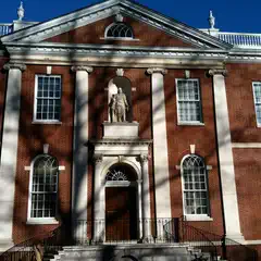 A red brick building with white columns and a statue above the entrance.