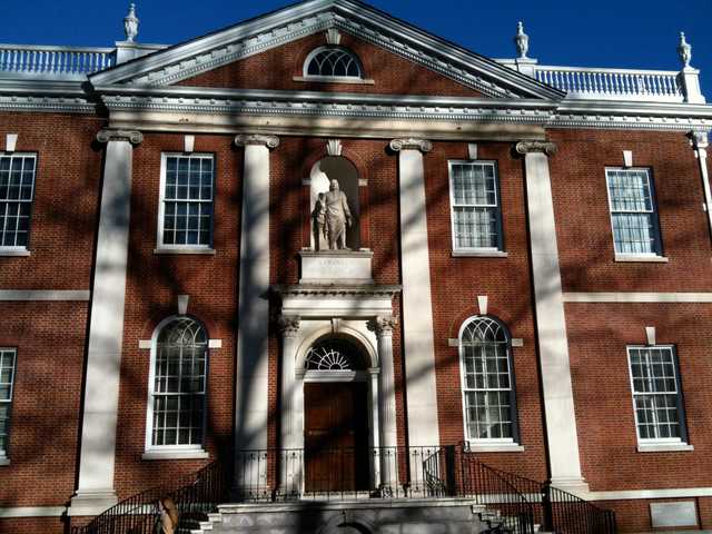 A red brick building with white columns and a statue above the entrance.