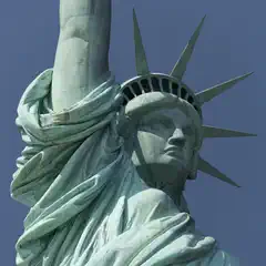 A copper statue depicts a woman wearing a crown and flowing robes, with an arm raised.