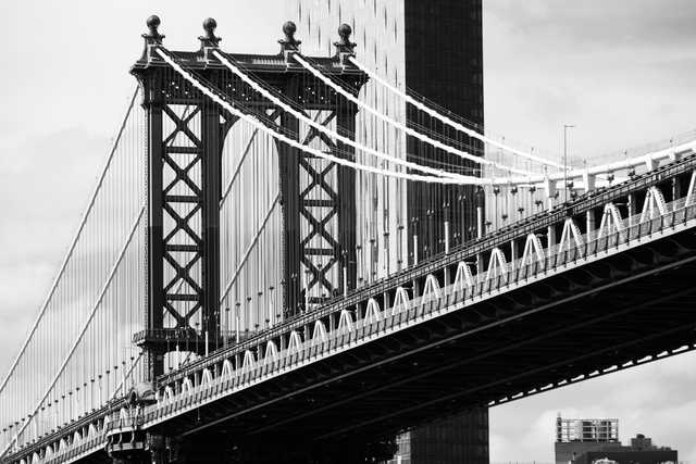 A steel suspension bridge extends diagonally across the frame, with a taller residential building visible behind it.