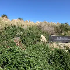 A sign reading "The Memory Garden" stands among various shrubs and grasses.