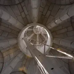 A metal staircase ascends through a cylindrical stone tower with arched windows.