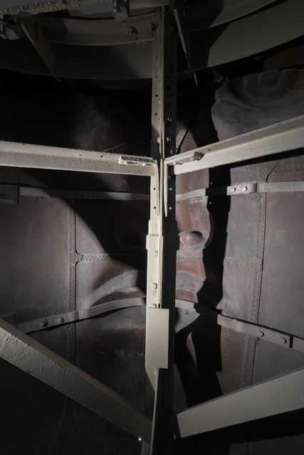 A metal structure with a face carved into it, partially obscured by bars and shadows.