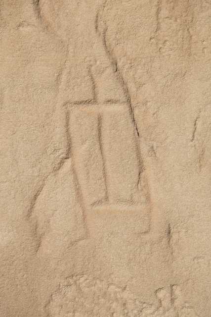 A beige rock face featuring a rectangular, humanoid petroglyph.