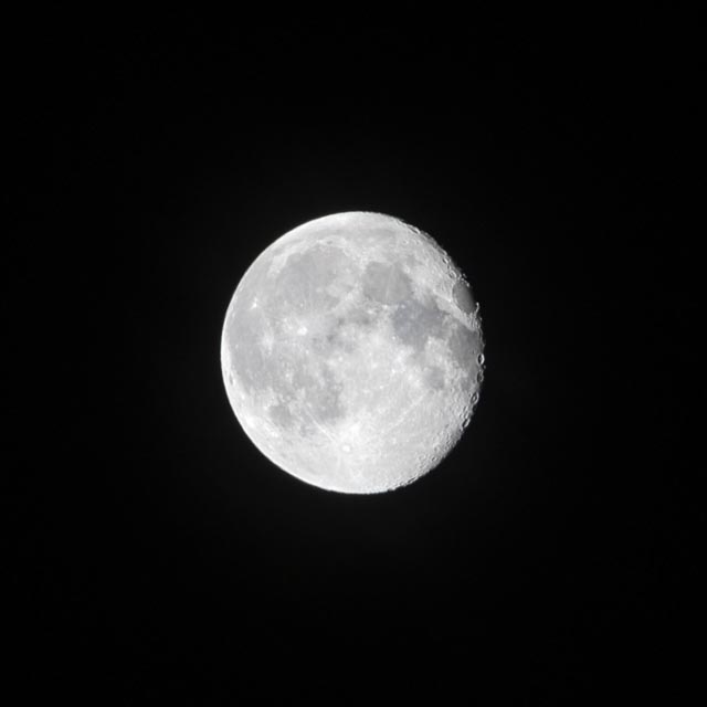 An almost full moon is shown at night against a black sky.