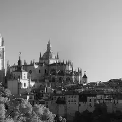 A large stone cathedral with multiple spires dominates a cityscape of smaller buildings and trees.