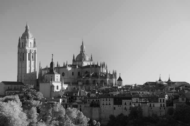 A large stone cathedral with multiple spires dominates a cityscape of smaller buildings and trees.