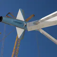 A blue and white jet aircraft is mounted on a white support structure, viewed from below, with a yellow crane visible in the background.