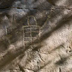 A section of rock art features a geometric pattern composed of squares, etched into the surface.