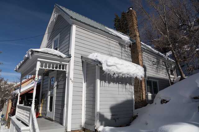 A white house with snow on its roof and melting icicles hanging off the eaves.