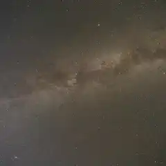 The Milky Way galaxy displays dense bands of stars and dust in the night sky.