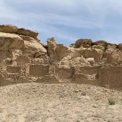 Ancient stone ruins on rocky terrain under clear sky.