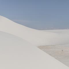 A white sand dune under a clear blue sky.