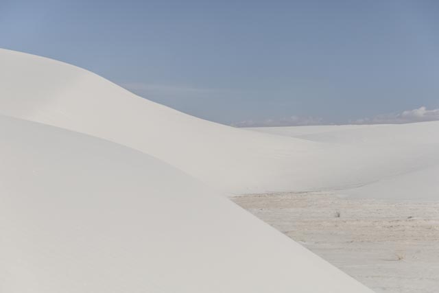 A white sand dune under a clear blue sky.