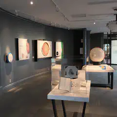 A room with a white table holding an exhibit about vision, surrounded by posters on the walls and a large screen displaying images of eyes.