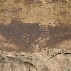 A rock face features a horizontal band of dark brown and yellow hues that gradually lightens toward the top, set against a lighter background.