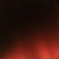 A night sky filled with stars, with a red glow on the horizon.