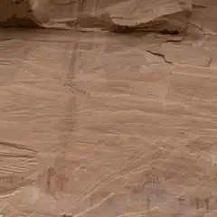 A sandstone wall displays numerous red pictographs.