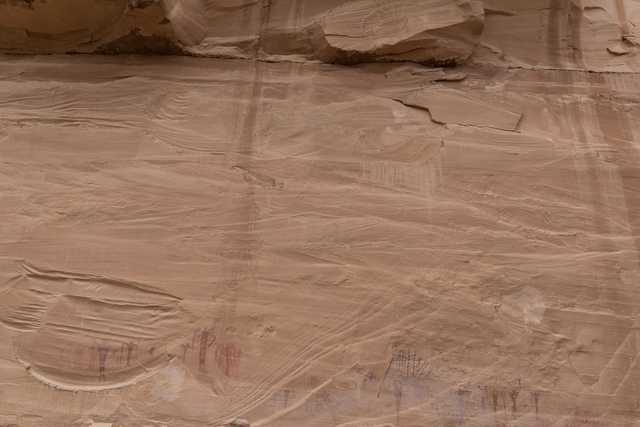 A sandstone wall displays numerous red pictographs.