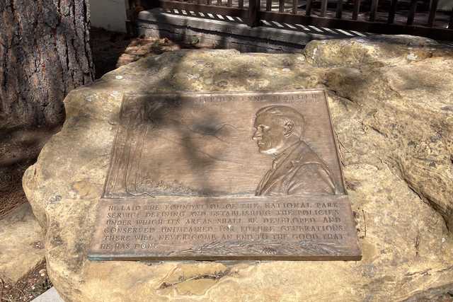 A bronze plaque with a relief portrait and text is mounted on a large, rough stone.