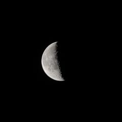 An illuminated half-moon against a black background.