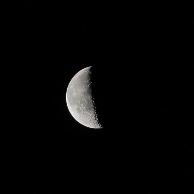 An illuminated half-moon against a black background.