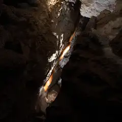 A narrow passage contains a vertical flow of white and orange mineral deposits.