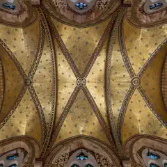A vaulted ceiling adorned with intricate gold mosaics, geometric patterns, and colorful stained glass windows.