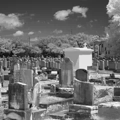 A cemetery with numerous headstones and a large white structure at its center.