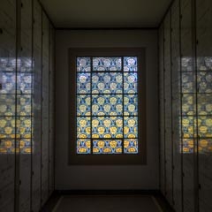 A stained glass window with a pattern of blue arches over yellow semicircles.