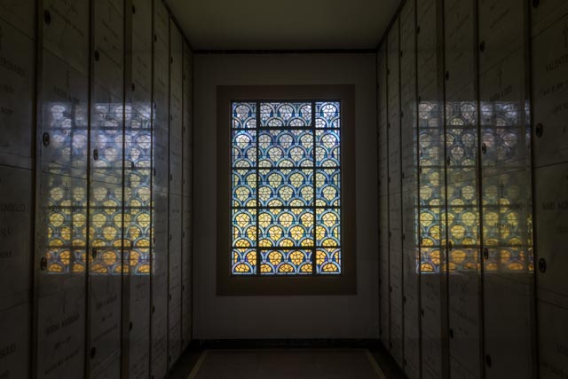 A stained glass window with a pattern of blue arches over yellow semicircles.