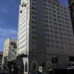 A tall building with many windows stands on a city street.