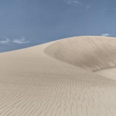 A large sand dune under a blue sky.