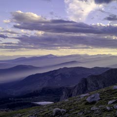 A mountainous landscape under a cloudy sky with sunlight streaming through gaps in clouds.