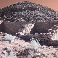 A stone ruin sits on a rocky hillside with sparse vegetation.