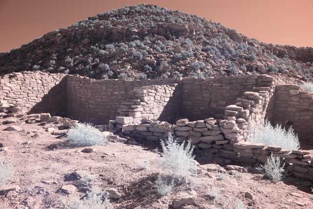 A stone ruin sits on a rocky hillside with sparse vegetation.