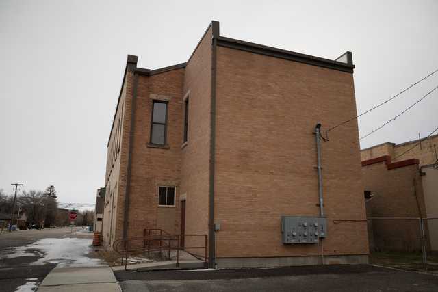 An old brick building constructed from red bricks, featuring a door and two windows on the visible side.