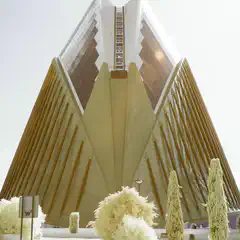 An angular building with a glass facade is visible behind a row of trees.