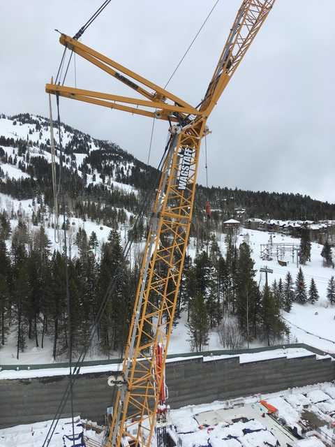A yellow crane stands over a snowy landscape, its boom extending into the sky.