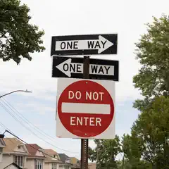 Conflicting traffic signs display 'ONE WAY' in opposite directions and a 'DO NOT ENTER' sign below.