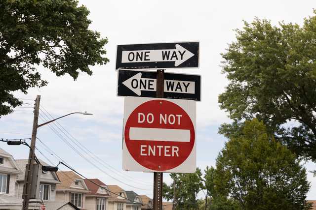 Conflicting traffic signs display 'ONE WAY' in opposite directions and a 'DO NOT ENTER' sign below.