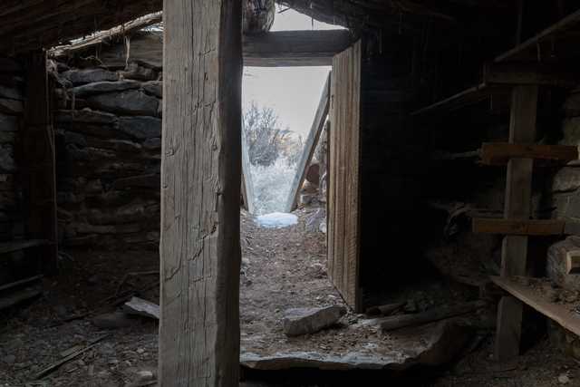 An old, dilapidated building interior with exposed wooden beams and stone walls.