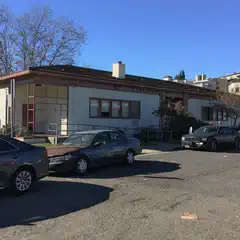 A white building with brown trim and a dark roof has a sign reading 'LAKEVIEW BRANCH LIBRARY' above its entrance.
