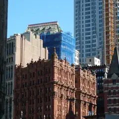 A dense urban skyline showcases a mix of historic and modern architecture under a clear blue sky.