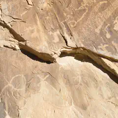 A rock face with ancient petroglyphs, showing signs of erosion and weathering.
