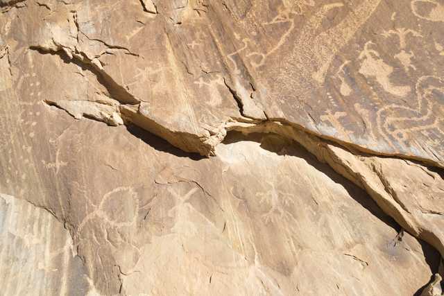 A rock face with ancient petroglyphs, showing signs of erosion and weathering.