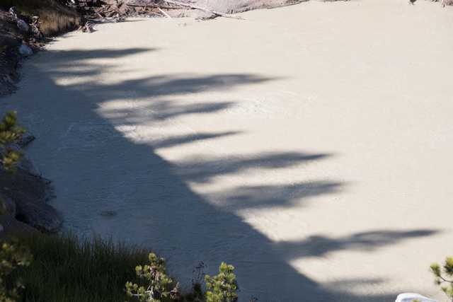 A murky body of water has a rippled surface that appears to be disturbed, likely due to strong currents or turbulent movement beneath the surface.