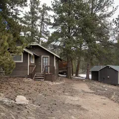 A row of small wooden cabins, each with a porch and steps leading up to it, situated on a rocky hillside surrounded by trees.