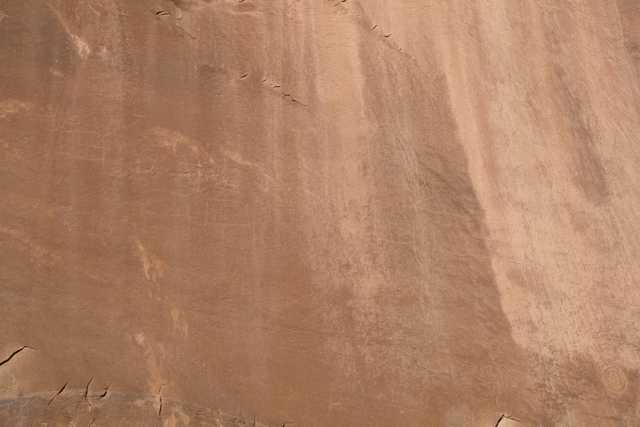 A large expanse of light brown rock with faint petroglyphs.