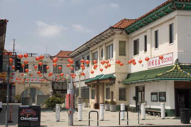 A street lined with buildings featuring Asian-style architecture and red lanterns hanging above.